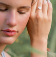Woman wearing a heart-shaped ring with a blurred green background