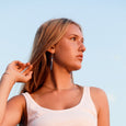 Woman wearing lapis earrings and blue jeans against a clear sky