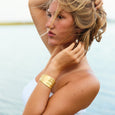 Woman with blonde hair and a gold bracelet against a light background